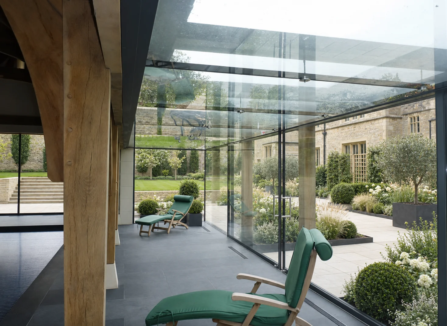 Glass extension with oak beams overlooking a contemporary landscaped garden