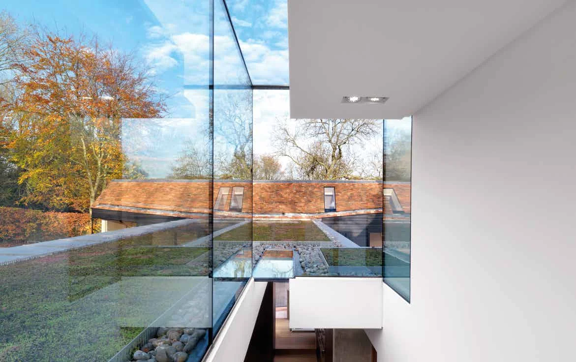 Frameless structural glazing overlooking a planted roof and garden