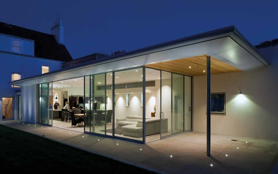 Contemporary glazed house extension with full-height glass walls at dusk